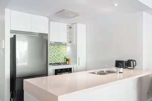 A modern kitchen with a stainless steel refrigerator, a gas stove, and a sink. - Front Row Convenience - Inner City- 3bed,2bath,2car (Brisbane)