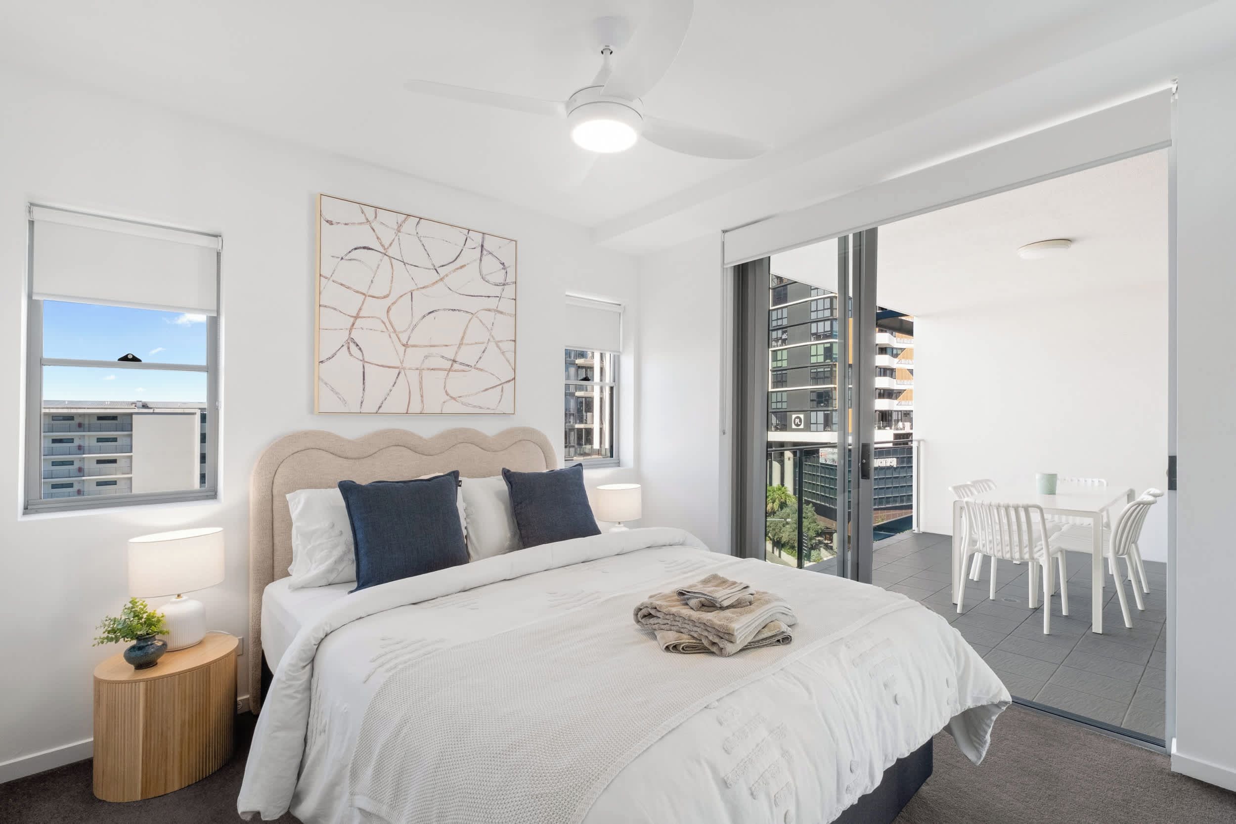 Een moderne slaapkamer met een groot bed, een plafondventilator, uitzicht op het balkon en een groot raam.