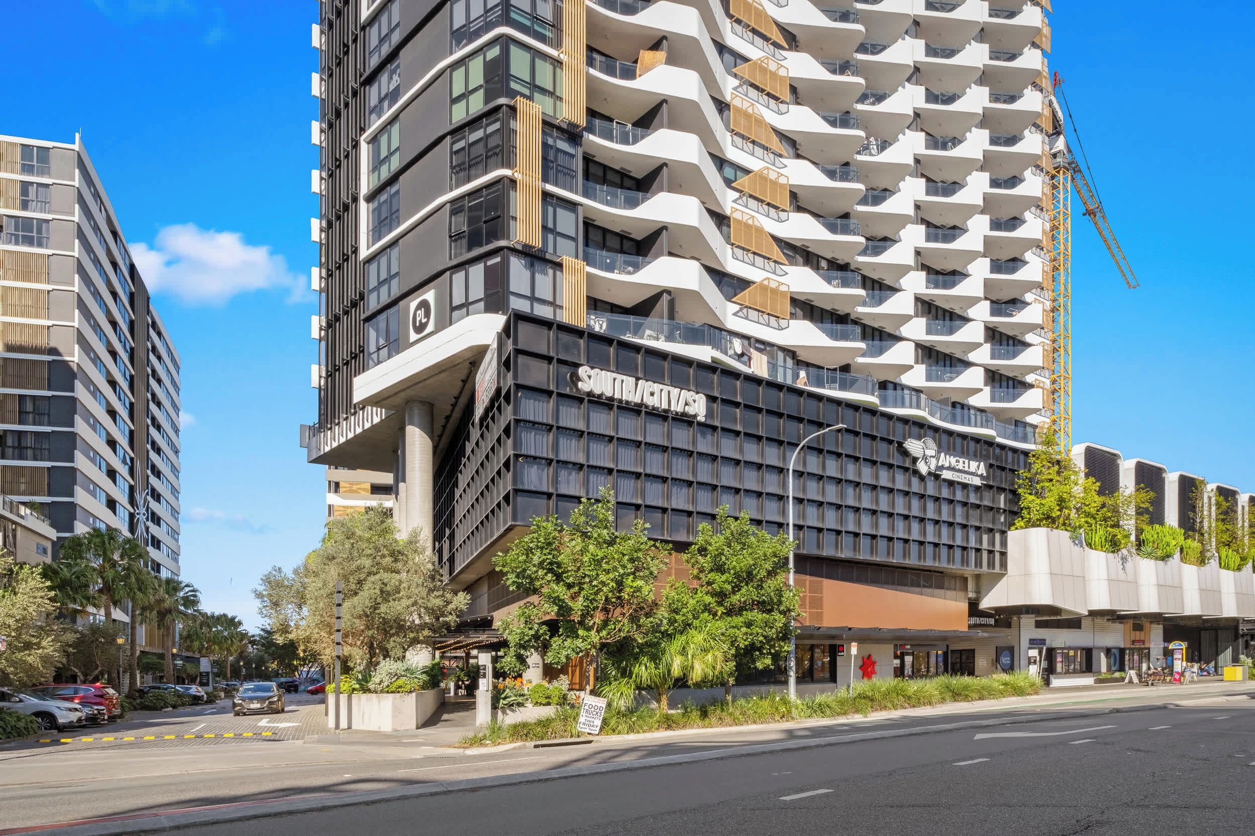 A modern high-rise building with a unique architectural design, featuring balconies and a prominent signage for a cinema.