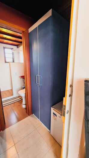 Een kamer met een kledingkast, een kleine koelkast en een toilet.