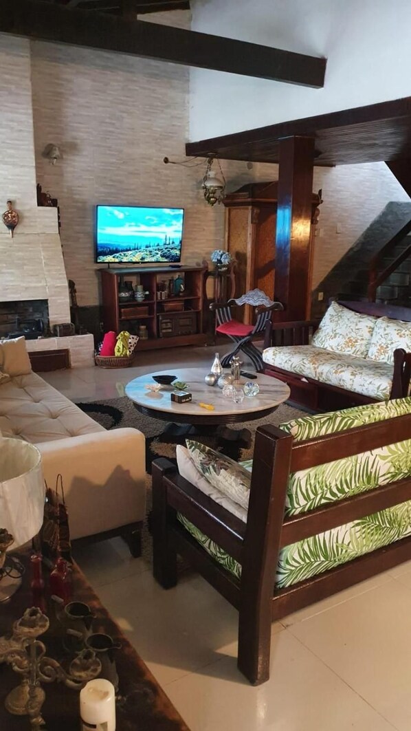 A living room with a fireplace, a television, a sofa, and a coffee table. - Hostel Lagoa Do Sol (Saquarema)