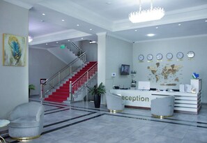 A reception area with a staircase, reception desk, and a world map on the wall. - Toshkent Grand Turon 1 (Tashkent)