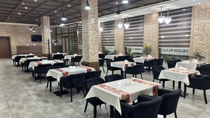 A restaurant with multiple tables and chairs, brick walls, and hanging lights. - Toshkent Grand Turon 1 (Tashkent)