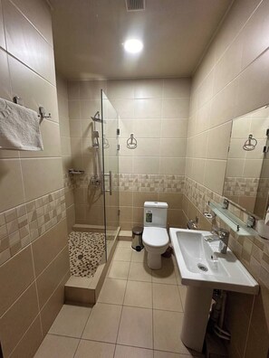 A bathroom with a shower, toilet, sink, and a glass-enclosed shower area. - Toshkent Grand Turon 1 (Tashkent)