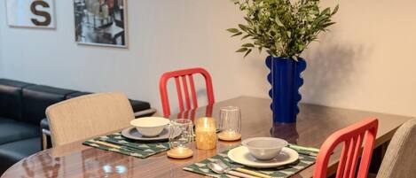 A dining table set with plates, bowls, glasses, and candles, surrounded by chairs.