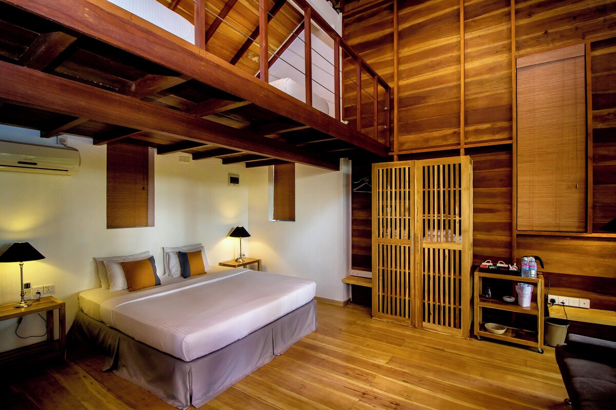 Quarto de madeira com cama, mesas de cabeceira, luminária e guarda-roupa de madeira.