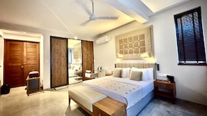 A modern bedroom with a large bed, a wooden bench, a ceiling fan, and a large mirror. - Palm Paradise Cabanas Ltd (Tangalle)