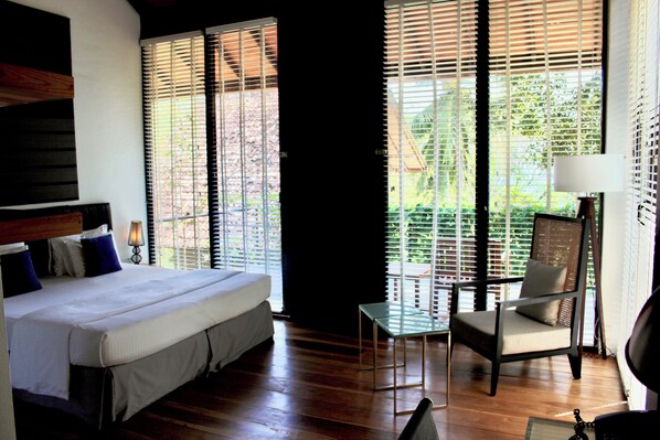 A hotel room with a bed, a chair, a small table, and a lamp.