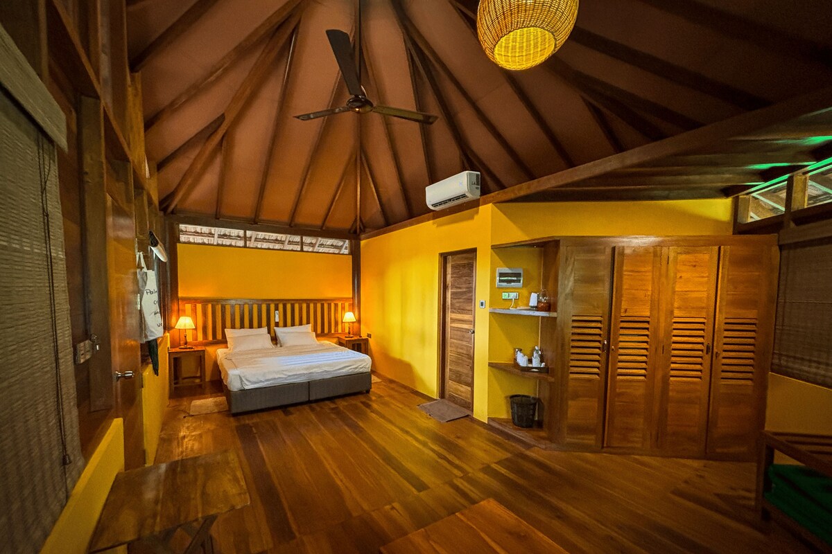 A room with a bed, a desk, a chair, a wardrobe, and a ceiling fan.