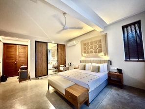 A modern bedroom with a large bed, a wooden bench, a ceiling fan, and a large mirror.