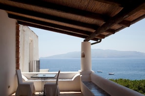 A balcony with a table and chairs, overlooking a body of water and distant mountains. - Hotel Santa Marina Antica Foresteria (Santa Marina Salina)