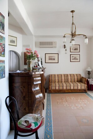 Una sala de estar con un sofá, un armario de madera, una silla y una alfombra estampada.