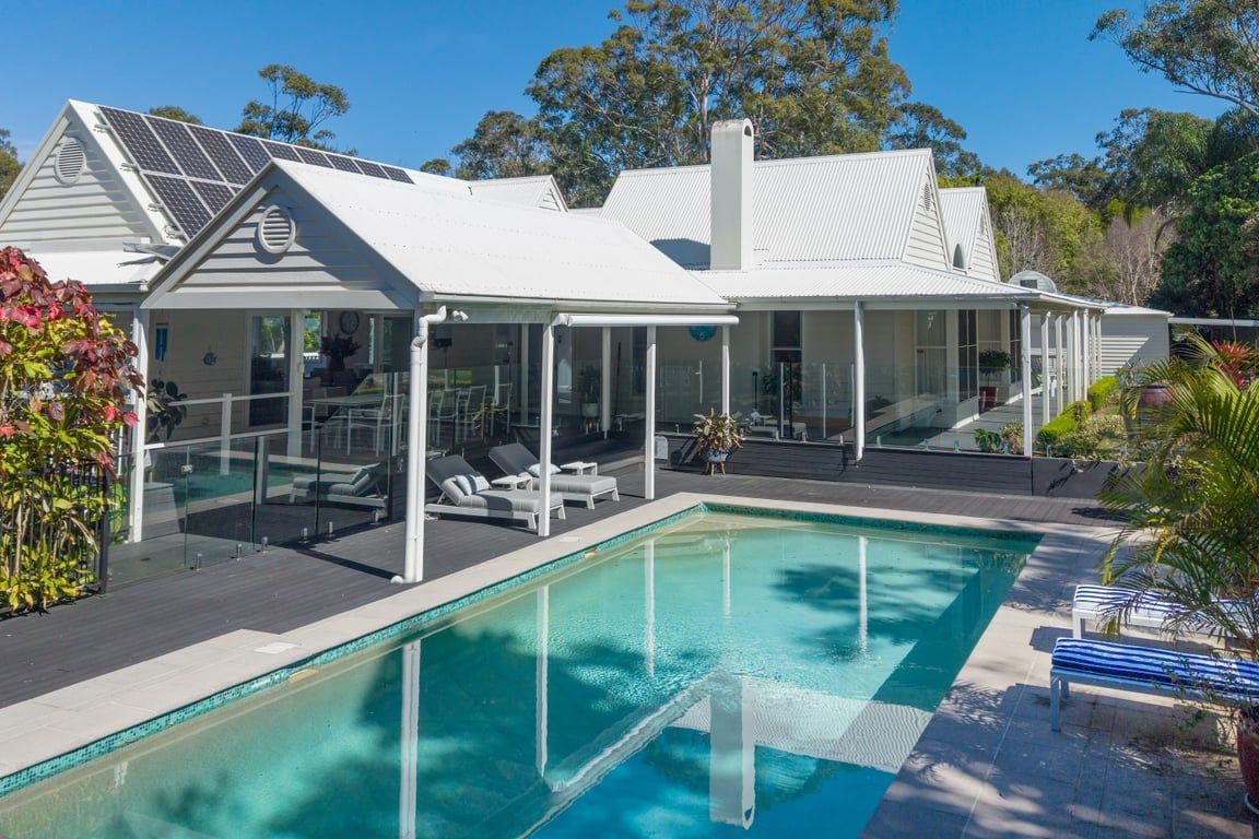 Ein modernes Haus mit Swimmingpool, einer verglasten Terrasse und Solaranlagen.