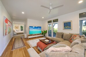 A modern living room with a flat-screen TV, a ceiling fan, and a large window with a view of the outdoors. - Treetops Retreat, Tinbeerwah (Tinbeerwah)