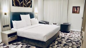 Ett hotellrum med en säng, sängbord, en stol och ett mönstrat golv.
