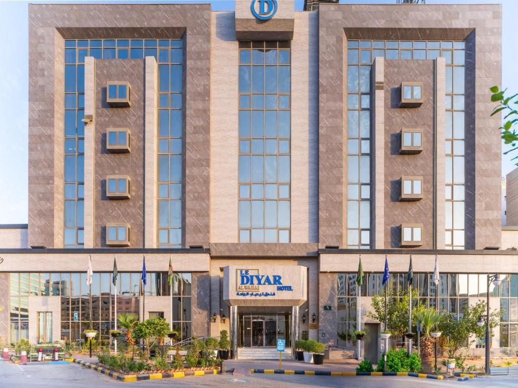 A hotel with a modern facade, large windows, and a sign indicating it's the Le Diyar Al Valihan Hotel.