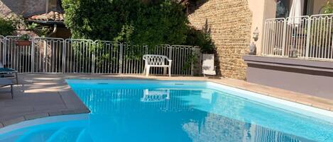 A swimming pool with a stone wall and a metal fence.