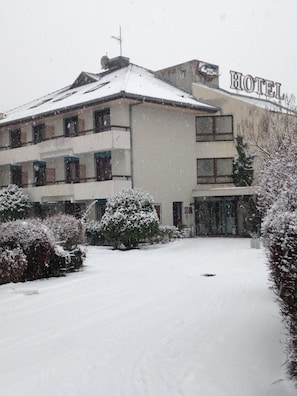 Um hotel com o telhado coberto de neve e uma placa com o nome.