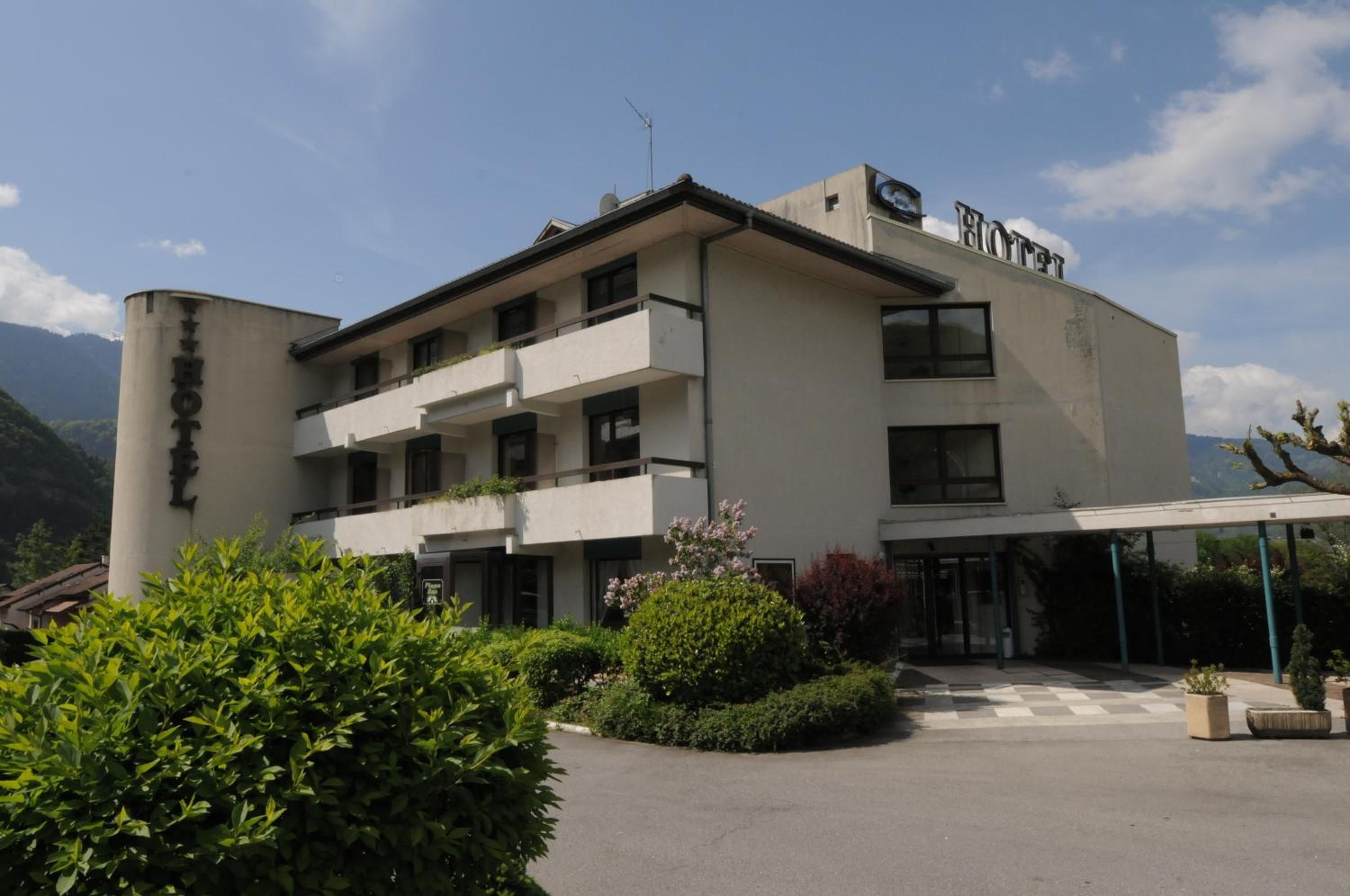 A hotel with a modern architectural style, featuring a flat roof, multiple balconies, and a covered entrance area.