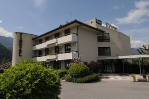 Een hotel met moderne architectuur, herkenbaar aan een plat dak, meerdere balkons en een overdekt entreegebied.