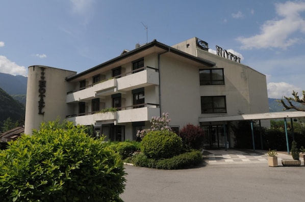 Um hotel com estilo arquitetônico moderno, apresentando telhado plano, várias varandas e uma área de entrada coberta.