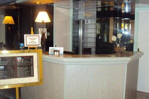 Una reception con un menu incorniciato e un cartello che indica gli orari della colazione.