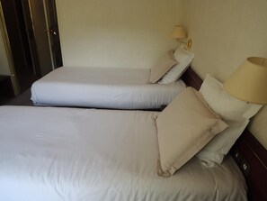 A hotel room with two beds, each with a pillow and a lamp. - Hôtel 4c (Cluses)