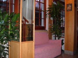 A staircase with a pink carpet leading to a landing, surrounded by wooden railings and potted plants.