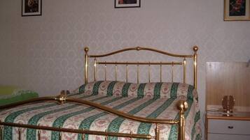 Une chambre avec un lit, une table de chevet et une commode.