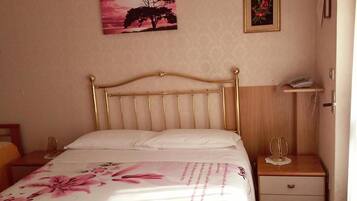 Un lit avec une tête de lit, une table de chevet avec une lampe et un mur orné de deux tableaux encadrés.