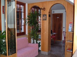 A room with a pink sofa, a wooden archway, a potted plant, and a red chair.