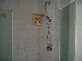 A shower with a handheld showerhead and a wall-mounted control panel.