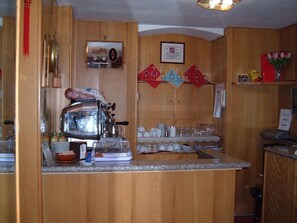 Una cocina con armarios de madera, una cafetera y diversos utensilios de cocina.