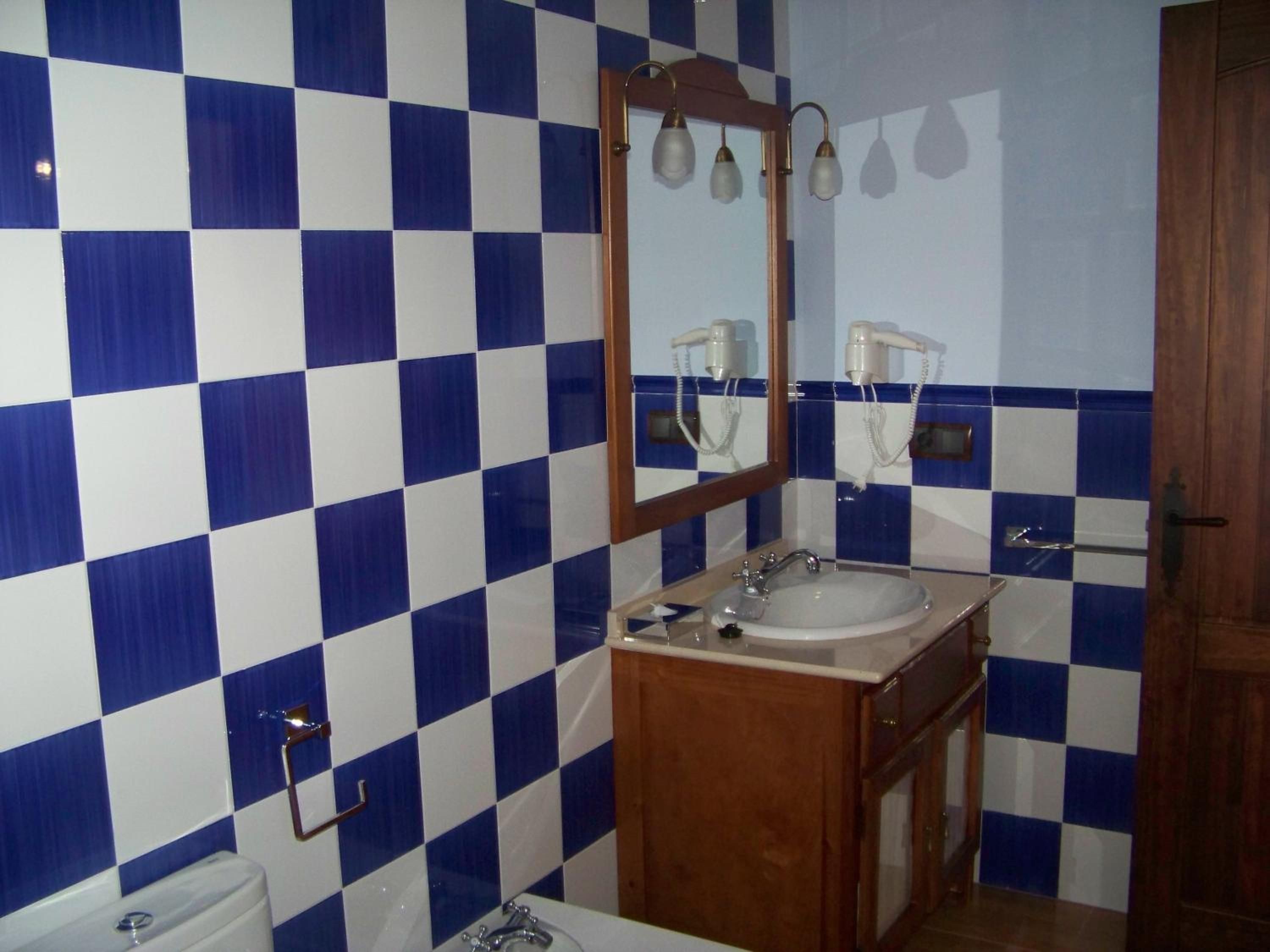 Un baño con piso de baldosas a cuadros, un lavamanos, un espejo y un inodoro.