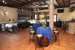 A restaurant interior with a bar area, stools, and a display case. - Hotel Rural Romero Torres (Fuente Obejuna)