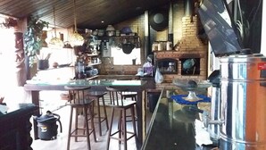 A kitchen with a brick wall, hanging pots, a coffee machine, and a large metal container. - Airport Pousada (Arraial do Cabo)