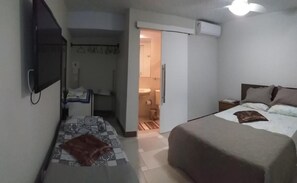 A compact hotel room with a bed, bedside table, and a television. - Airport Pousada (Arraial do Cabo)