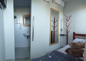 A bedroom with a bed, a bedside table, a mirror, and a wardrobe. - Airport Pousada (Arraial do Cabo)