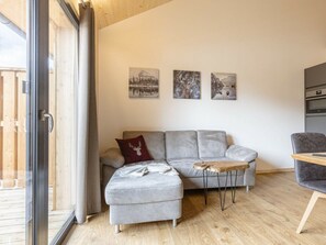 A modern living room with a grey sofa, a small ottoman, and a wooden coffee table. There are three framed pictures on the wall. - Apartment With 1 Bedroom (Sankt Georgen am Kreischberg)