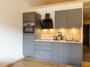 A modern kitchen with grey cabinetry, a built-in oven, a coffee maker, and a toaster. - Apartment With 1 Bedroom (Sankt Georgen am Kreischberg)