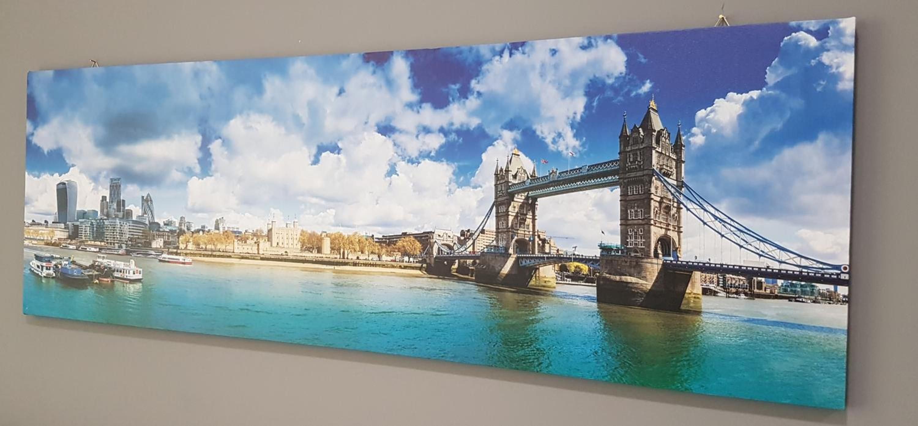 A panoramic view of a river with a bridge and cityscape, including a prominent tower.