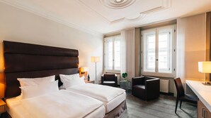 A hotel room with a large bed, two bedside tables, a desk, a chair, and a window with curtains. - Amtshaus Freinsheim (Freinsheim)