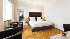 A hotel room with a double bed, bedside tables, a seating area with a chair, a small table, and a vase with flowers. - Amtshaus Freinsheim (Freinsheim)