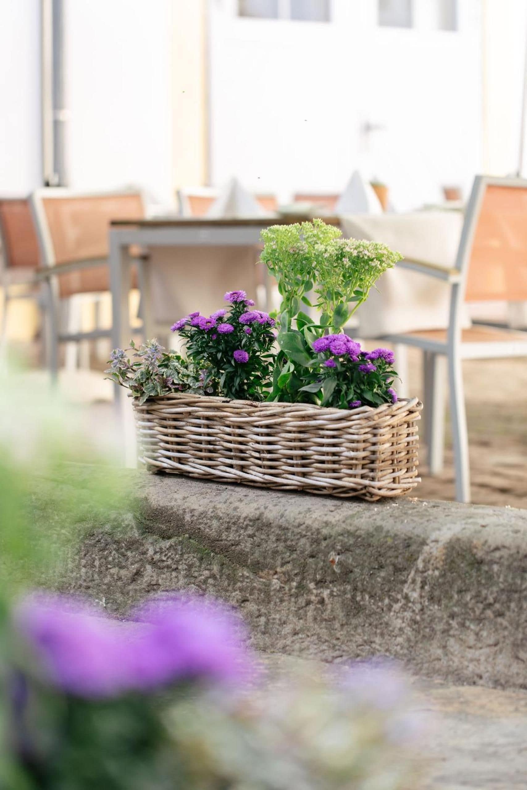 A wicker basket with flowers on a stone ledge.