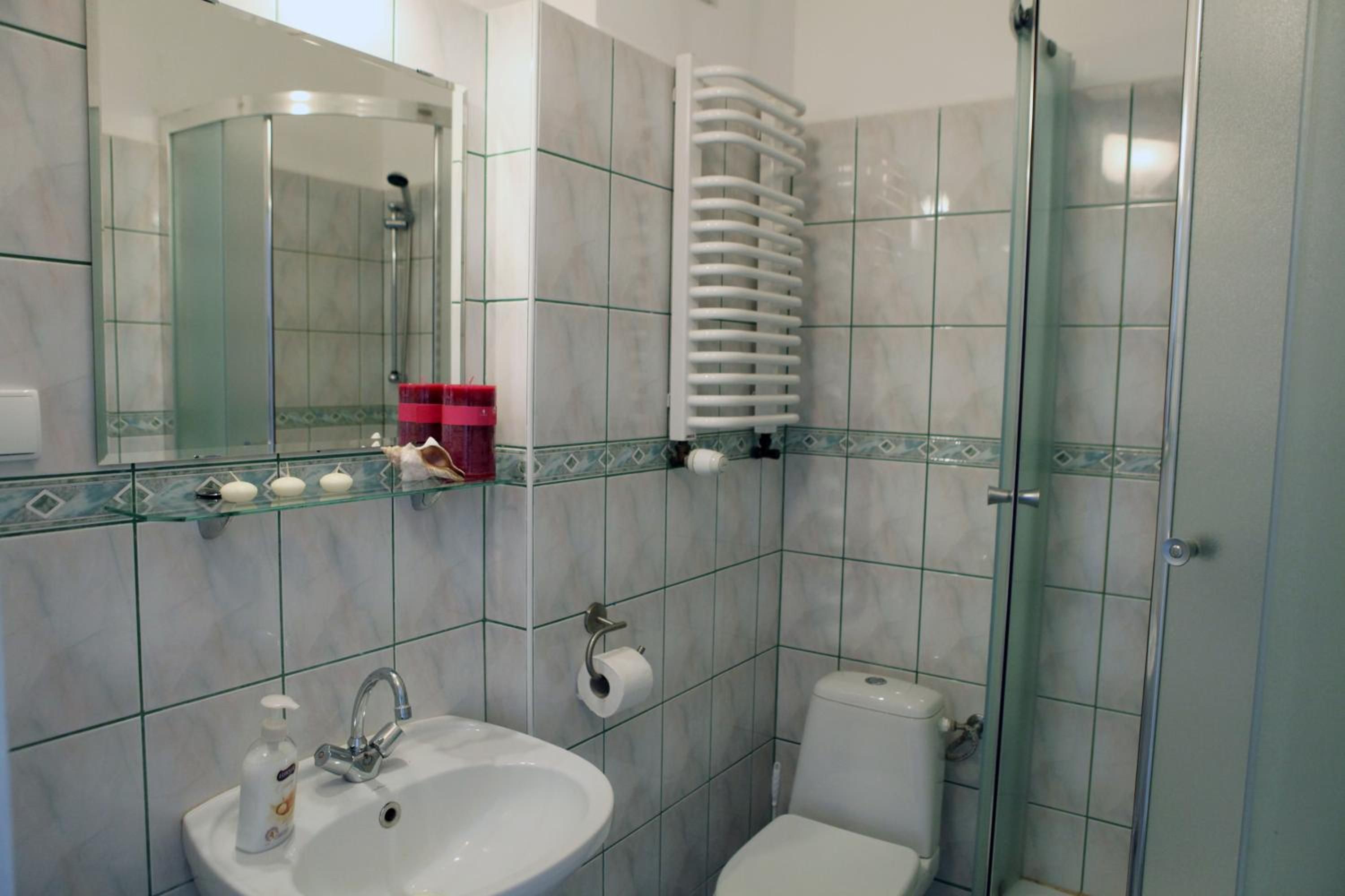 Un baño con cabina de ducha de vidrio, un lavamanos con dispensador de jabón y un inodoro.