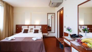 A hotel room with a bed, bedside table, desk, and a mirror.