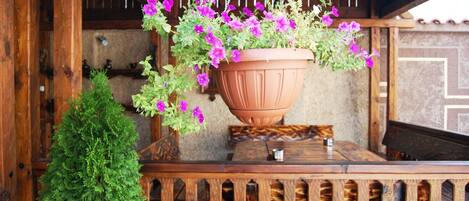 A hanging flower pot with purple flowers on a wooden table.