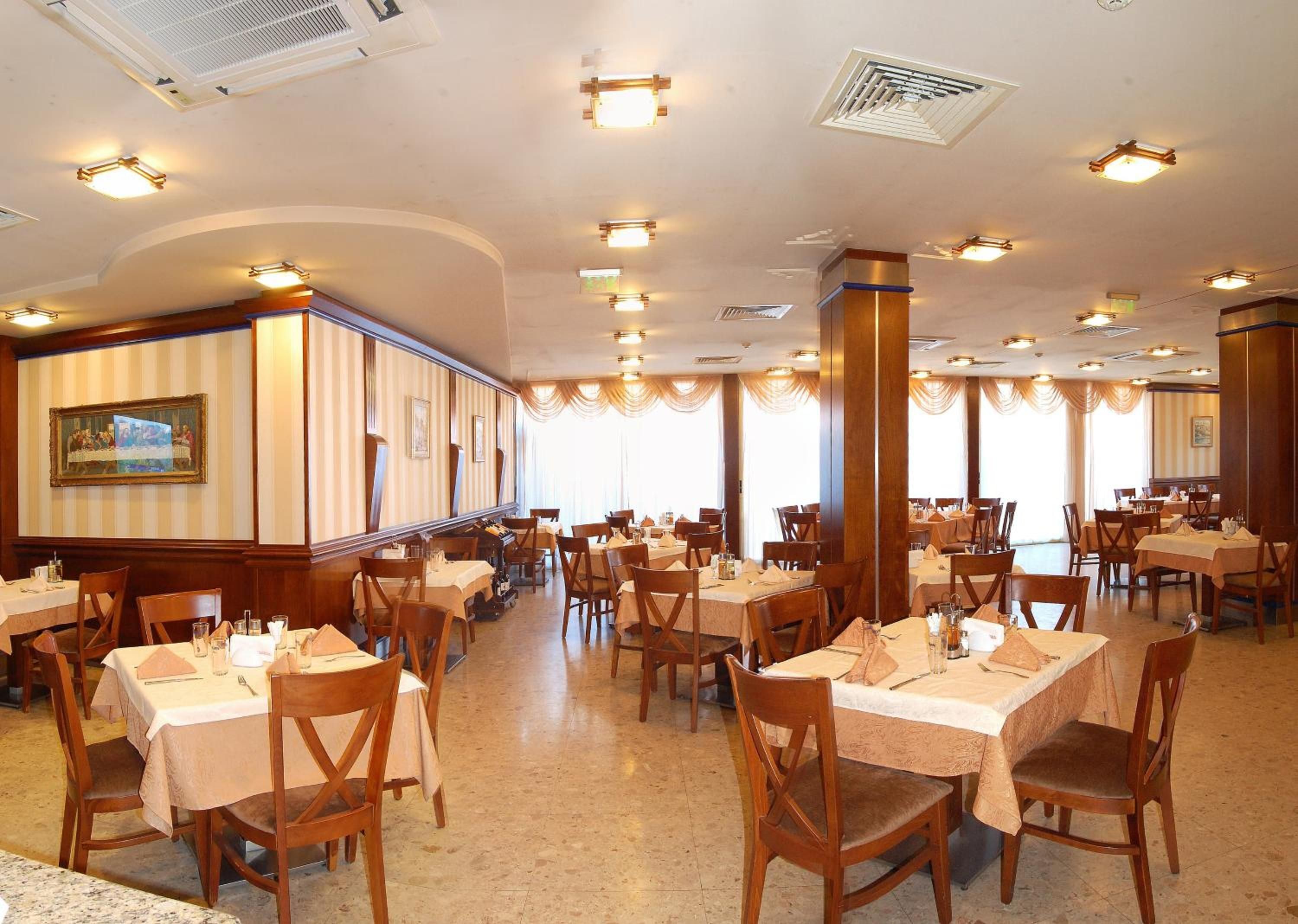 A spacious dining area with multiple tables and chairs, large windows, and a central column.