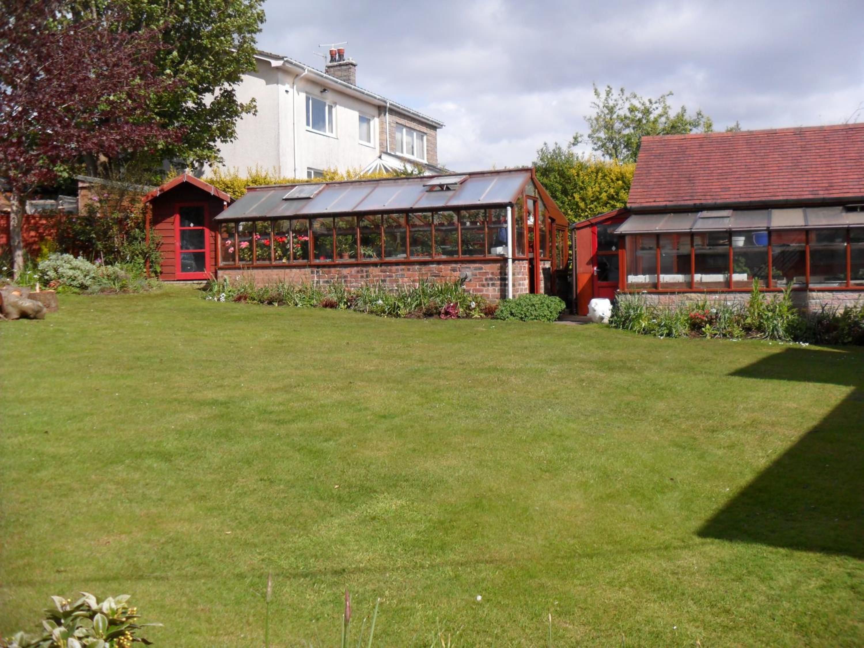 A residential property with a large lawn, a conservatory, and a detached house.