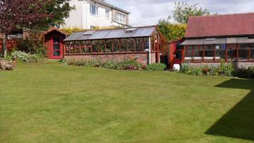 A residential property with a large lawn, a conservatory, and a detached house.